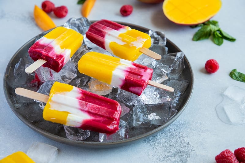 colorful healthy looking mango and berry popsicles